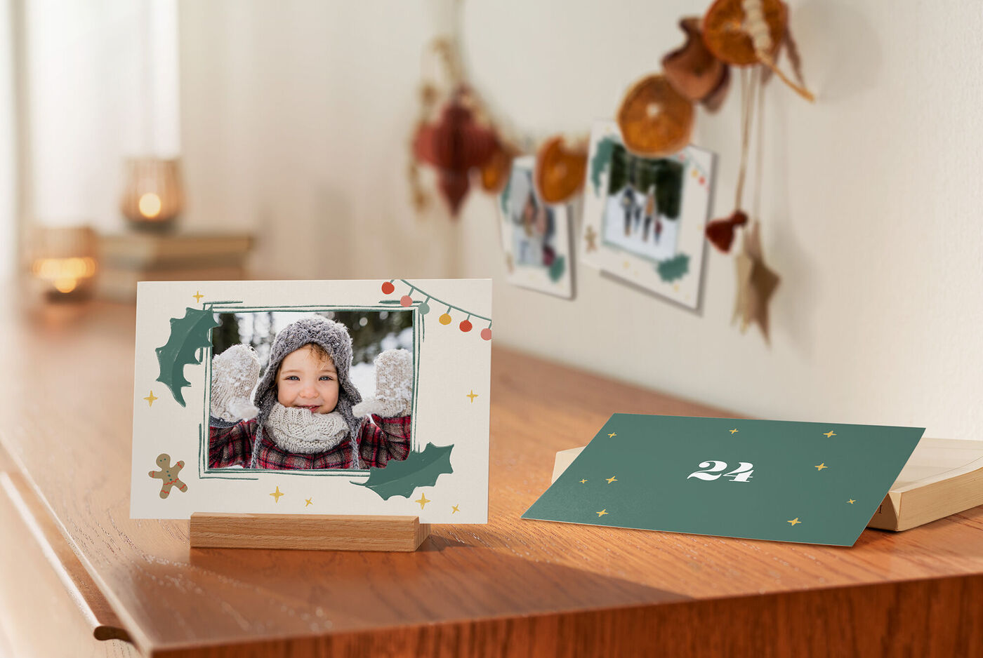 Eine Karte des Tisch-Adventskalender mit dem Foto eines Kindes im Holzaufsteller auf einem Tisch und eine Karte im weihnachtlichen Design.