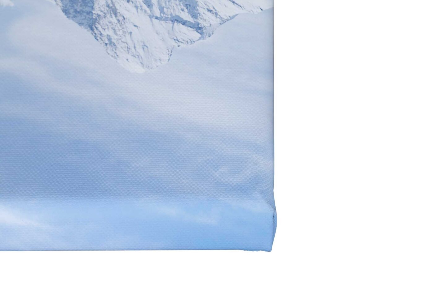 Ein Teil einer Fotoleinwand von CEWE mit einem Bergmotiv mit blauem Himmel auf einem zwei Zentimeter starken Keilrahmen.