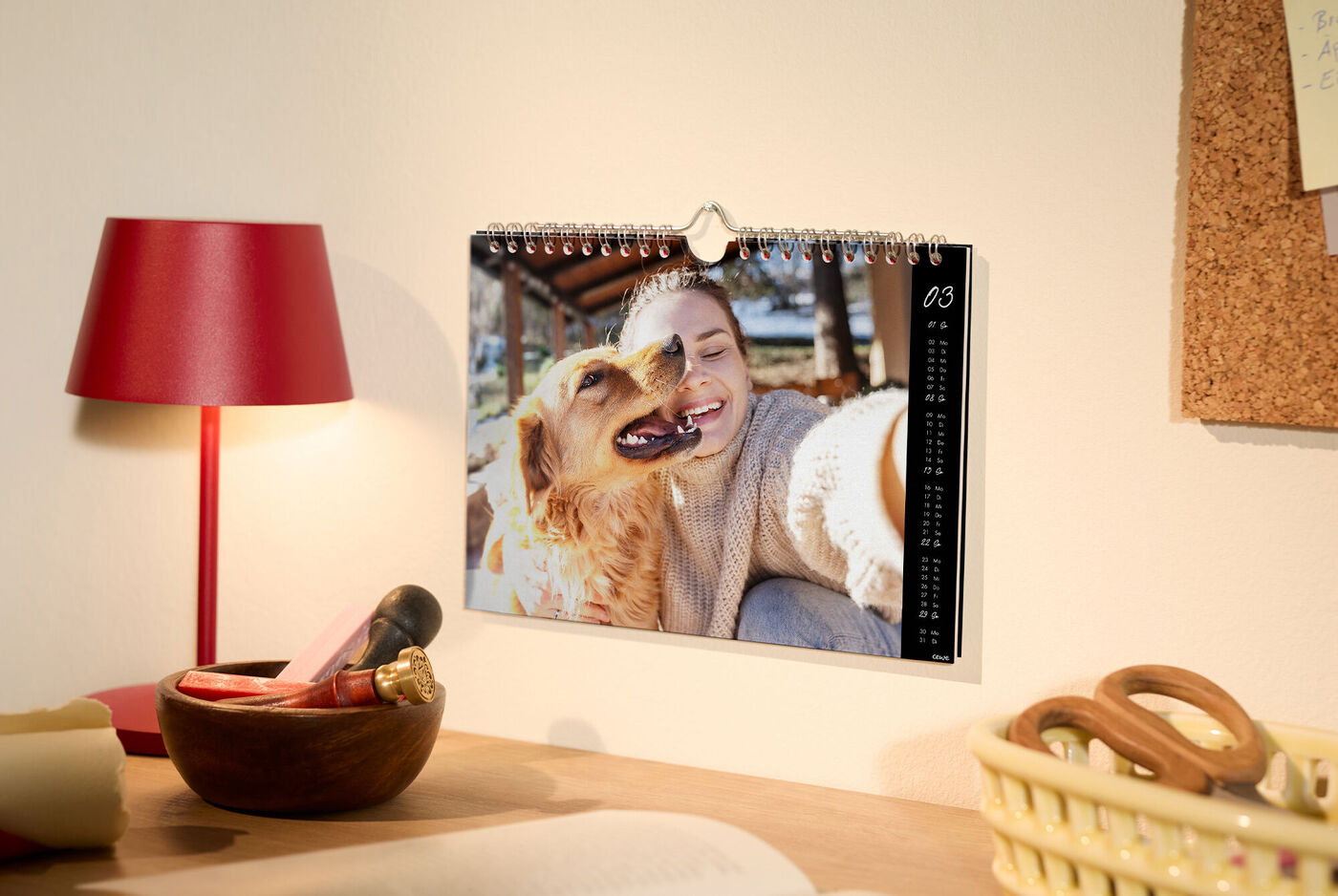 Ein CEWE Fotokalender mit einem süßen Hundebild hängt an der Wand.