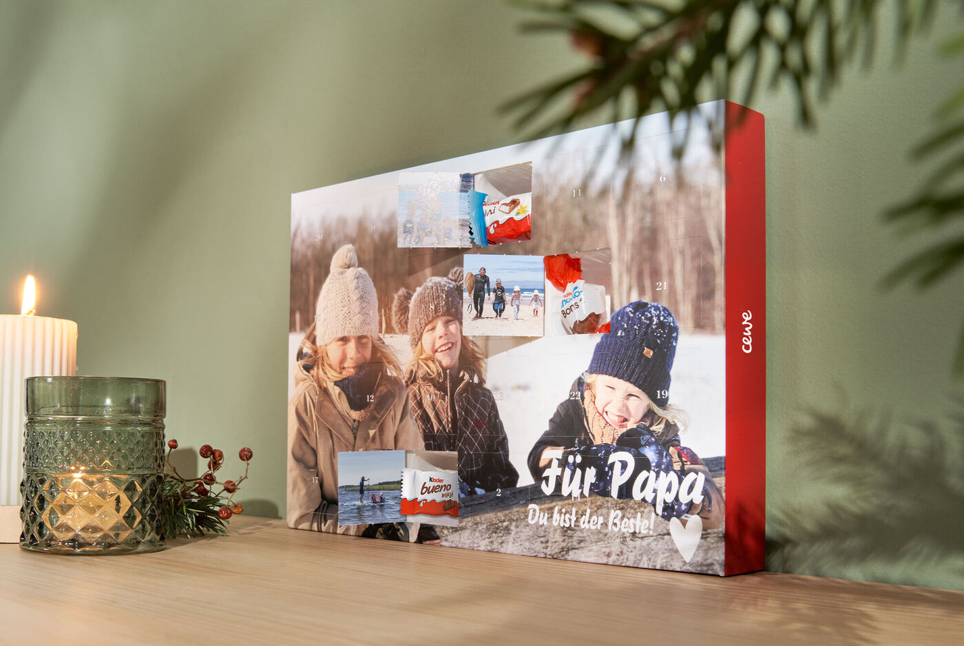Adventskalender gefüllt mit Schokolade von kinder und Türchendruck. Mit teilweise geöffneten Türchen und dem Foto einer Familie im Schnee.